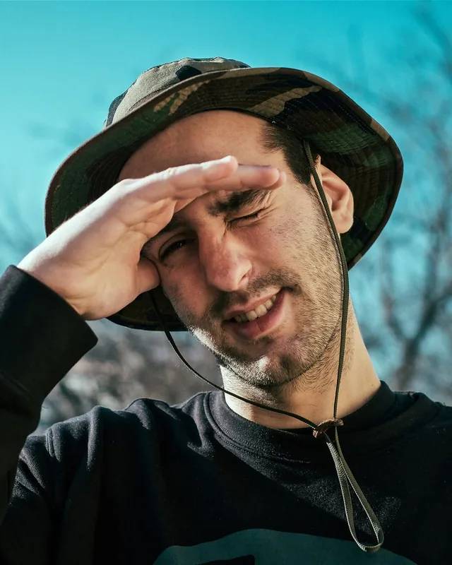 Lyubomir Petrov in a camouflage bucket hat, shielding his eyes from the sun