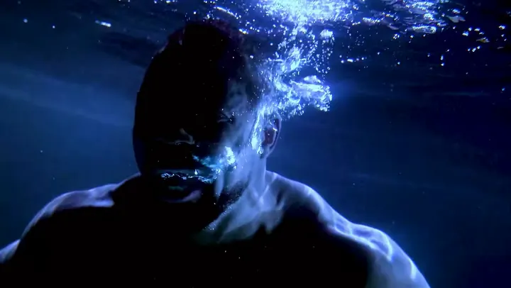 An athlete’s face underwater, in blue